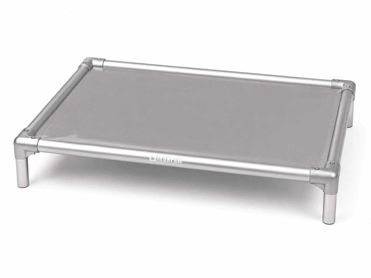 Commercial studio product photo of the Mist Elevated Dog Bed with glossy neutral grey PVC fabric, brushed silver aluminium frame, rounded corner connectors, bare tube legs, visible hex screws, and centred pale IronPaw engraving on the front rail.